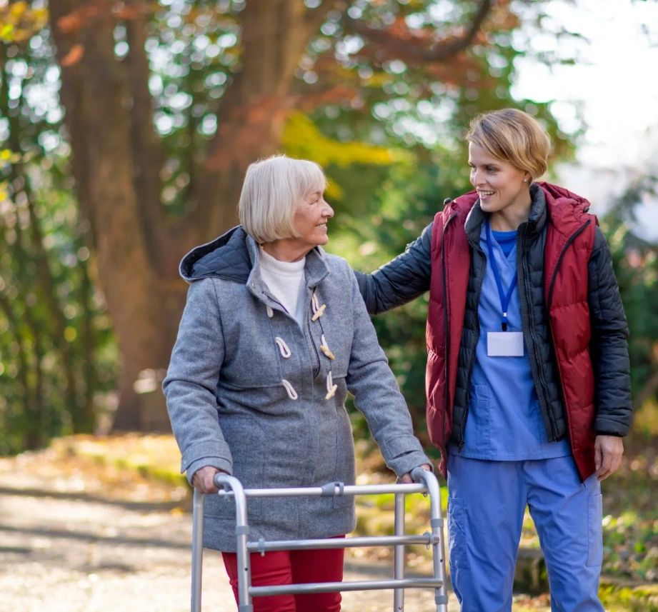 Caregiver walking outdoors with elderly woman