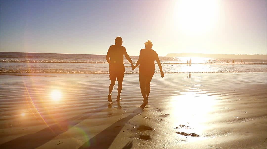 Couple walking on beach at sunset